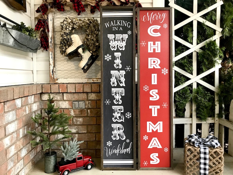 May include: Two wooden signs with black and red paint. The sign on the left says "Walking in a Winter Wonderland" and the sign on the right says "Merry Christmas".