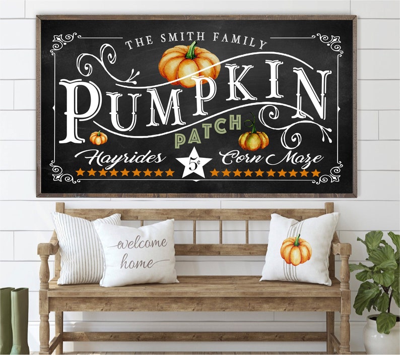 May include: A black chalkboard sign with white lettering that reads "The Smith Family Pumpkin Patch Hayrides 5&cent; Corn Maze". The sign is decorated with orange pumpkins and stars.