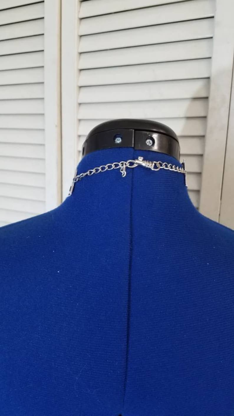 May include: A silver chain necklace with a clasp closure. The necklace is displayed on a blue mannequin.