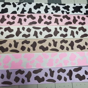 May include: Five different cow print ribbons in various colors, including black, white, pink, brown, and purple.