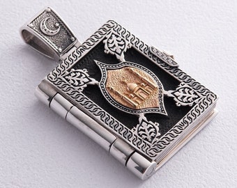 May include: A silver and gold pendant in the shape of a book with intricate details. The book features a crescent moon and a mosque design.