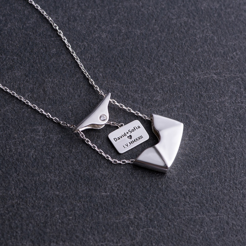 May include: Silver necklace with a pendant that says "David + Sofia" with a heart symbol and the date "I.V.MMXXII".