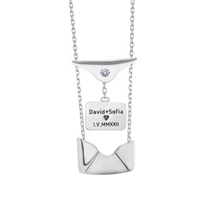 May include: Silver necklace with a small diamond and a pendant that says "David+Sofia I.V.MMXXII" with a heart symbol.