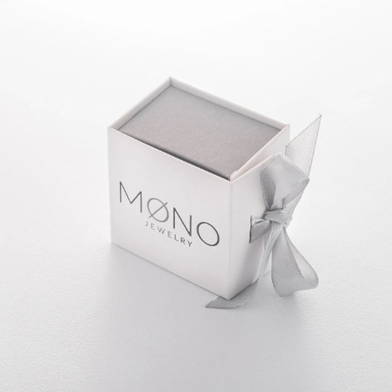 May include: A white jewelry box with a gray lid and a silver ribbon. The box has the text "MONO JEWELRY" printed on the front.