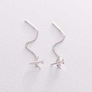 May include: A pair of silver airplane dangle earrings with a delicate chain.