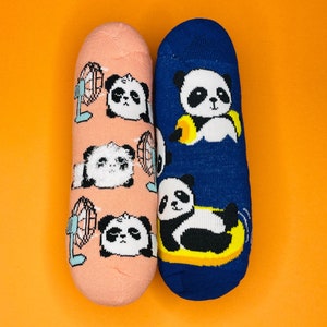May include: A pair of socks with panda designs. One sock is pink with pandas holding fans and the other is blue with a panda on a yellow float.