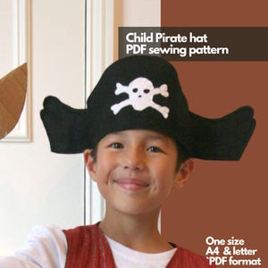 Può includere: Un bambino indossa un cappello da pirata in feltro nero con un design di teschio e ossa incrociate bianche. Il cappello è di taglia unica e viene fornito in formato di modello di cucito PDF. Il testo "Child Pirate hat PDF sewing pattern" e "One size A4 & letter PDF format" è visibile nell'immagine.