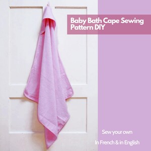 Peut inclure: Une cape de bain pour bébé rose clair avec une capuche est suspendue à une porte blanche. Le texte "Baby Bath Cape Sewing Pattern DIY" est dans un rectangle rose. Le texte "Sew your own In French & in English" est en bas à droite.