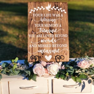 May include: A wooden sign with a white heart and the text "YOUR LIFE WAS A blessing YOUR MEMORY A treasure YOU ARE LOVED BEYOND words AND MISSED BEYOND measure"