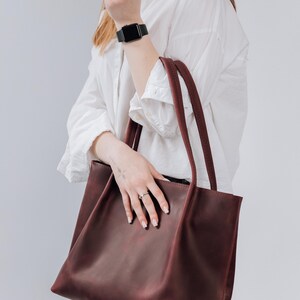 May include: A burgundy leather tote bag with two handles. The bag is large enough to carry everyday essentials.