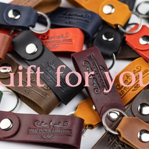 May include: A collection of leather keychains with different colors and designs. The keychains feature the text "Old Town Leather" and various decorative elements.