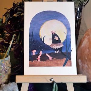 May include: A watercolor painting of a mole wearing a pink tutu and dancing under a full moon. The mole is black with a pink nose and a pink flower on its head. The moon is yellow and the background is a dark blue with white stars.