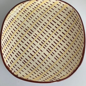 Puede incluir: Un bol de servir de cerámica blanca con un borde marrón y un patrón de cruz en amarillo.