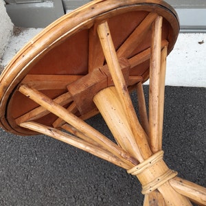 Puede incluir: Una mesa redonda de madera con una base de rat&aacute;n tejido. La tapa de la mesa es de madera y tiene un acabado natural. La base es de rat&aacute;n tejido y tiene un acabado natural.