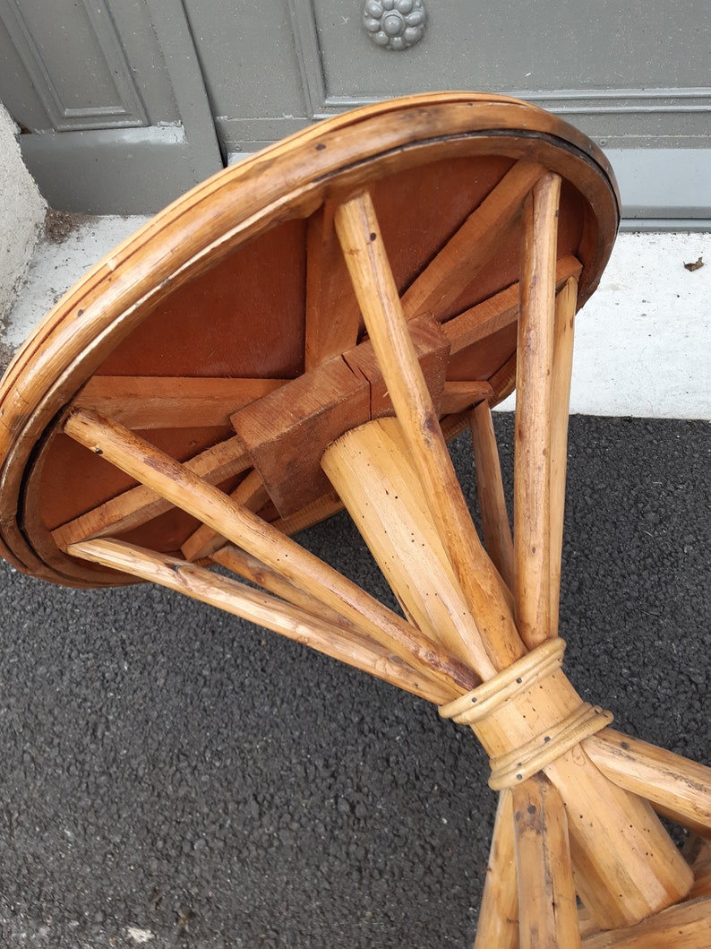 Puede incluir: Una mesa redonda de madera con una base de rat&aacute;n tejido. La tapa de la mesa es de madera y tiene un acabado natural. La base es de rat&aacute;n tejido y tiene un acabado natural.