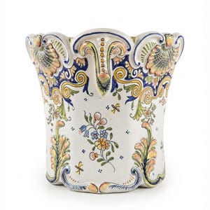 May include: A ceramic planter with a scalloped rim, featuring a white base decorated with hand-painted floral motifs in blue, yellow, green, and orange. The exterior displays intricate scrollwork and leaf patterns along the top and base edges.
