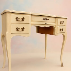 Pode incluir: Penteadeira creme com pernas curvas e puxadores de gaveta de latão ornamentados. A escrivaninha tem várias gavetas e uma abertura central para uma cadeira. O design é vintage e elegante, adequado para um quarto ou camarim.