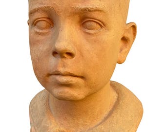 May include: A terracotta bust of a young boy with short hair and a collared shirt. The sculpture has a natural, weathered appearance. The text "Mildebrand" is visible on the base. A classic piece of art.