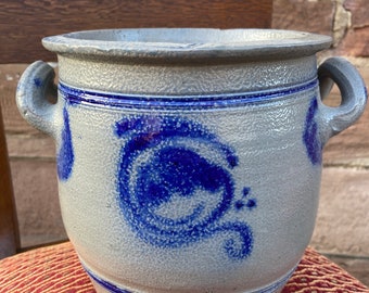 Peut inclure: Une cruche en grès gris avec des motifs peints en bleu. La cruche a deux anses et une large ouverture.