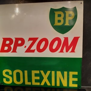 May include: A vintage BP-Zoom and Solexine sign. The sign has a white background with red text reading "BP-ZOOM" and yellow text reading "SOLEXINE". A green shield with yellow "BP" lettering is at the top.
