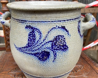 Peut inclure: Une grande cruche en grès gris avec un motif floral bleu et blanc. La cruche a deux anses et une surface texturée.