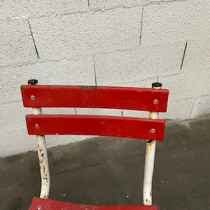 May include: Red metal chair with white painted legs and a white background.