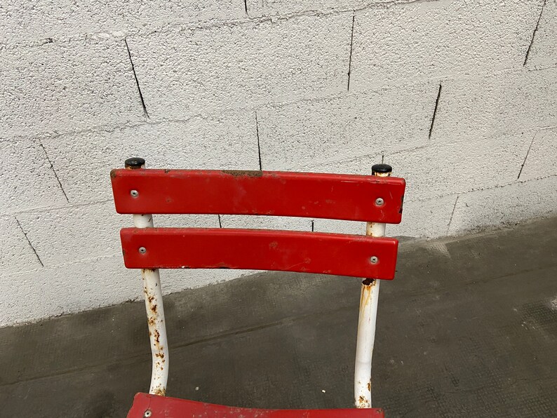May include: Red metal chair with white painted legs and a white background.