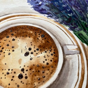 May include: A close-up of a cup of coffee with a brown frothy top. The cup is white with a gold rim and is sitting on a white saucer with a gold rim. A bouquet of lavender flowers is in the background.