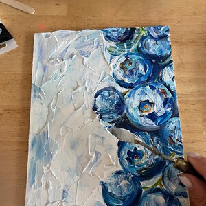 May include: An original painting of blue flowers with a palette knife. The artwork features textured white and light blue paint on a rectangular canvas. The flowers are painted in shades of blue with green accents.
