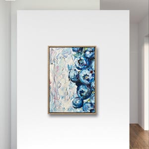May include: An original oil painting on canvas, featuring a cluster of stylized blue flowers with white and light blue textured brushstrokes. The artwork is framed in a natural wood tone and mounted on a white wall.