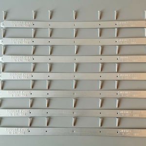 May include: Ten silver metal shelf support brackets with pre-drilled holes. Each bracket has the text "SUPPORT EVERY 1.2H. MAX" printed on it.
