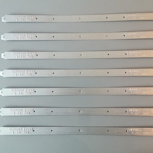 May include: Seven silver metal strips with the text "SUPPORT EVERY 1.2H. MAX" printed on each strip.