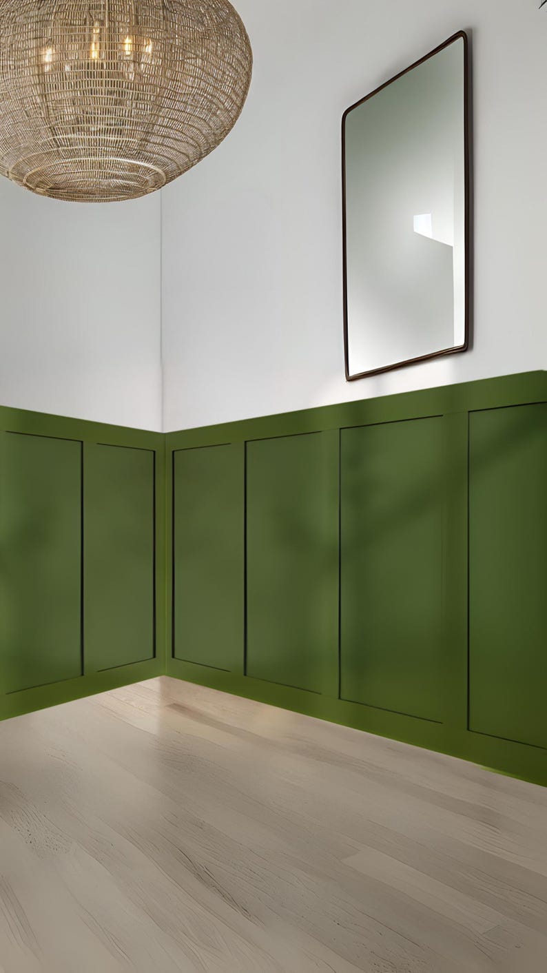 May include: A room with a light wood floor and green wainscoting. A woven light fixture hangs from the ceiling. A rectangular mirror with a dark wood frame hangs on the wall.