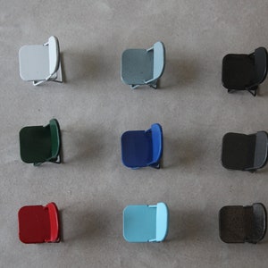 May include: Nine folding chairs in different colors, including white, light blue, dark blue, green, black, red, and brown. The chairs are arranged in three rows of three.