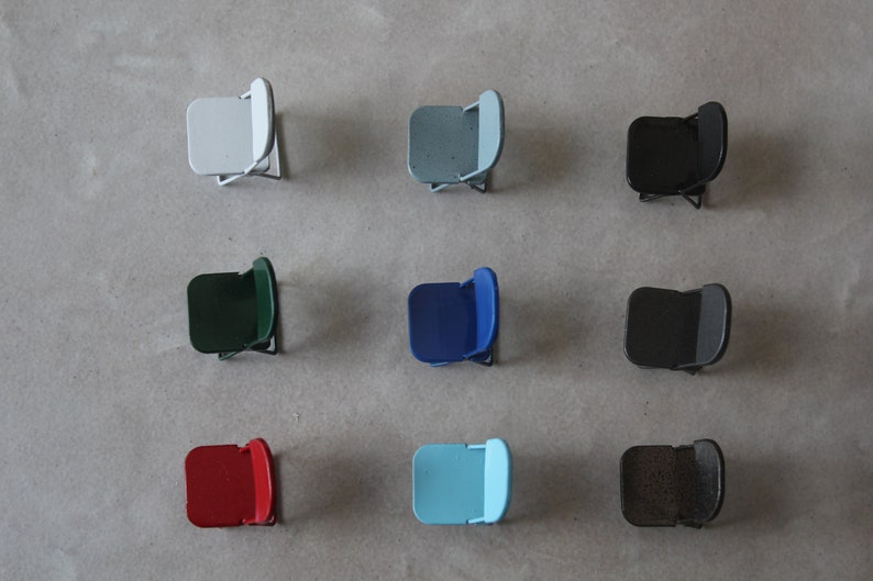 May include: Nine folding chairs in different colors, including white, light blue, dark blue, green, black, red, and brown. The chairs are arranged in three rows of three.