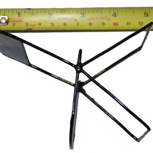 May include: A black metal stand with three legs and a flat top. The stand is about 5 inches wide.