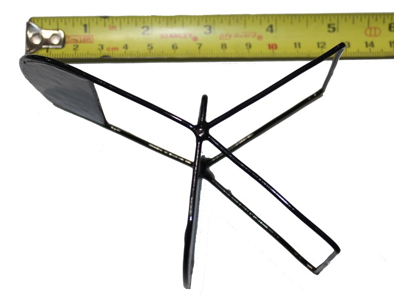 May include: A black metal stand with three legs and a flat top. The stand is about 5 inches wide.
