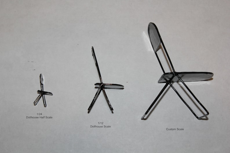 May include: Three black metal chairs in different sizes. The chairs are made of thin metal and have a simple design. The smallest chair is labeled "1/24 Dollhouse Half Scale", the middle chair is labeled "1/12 Dollhouse Scale", and the largest chair is labeled "Custom Scale".