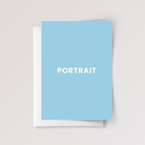 May include: A light blue rectangular greeting card with the word PORTRAIT printed in white capital letters in the center. The card is positioned slightly offset, revealing a plain white card base underneath the light blue top layer.