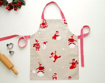 Può includere: Grembiule natalizio beige con finiture e spalline a righe rosse e bianche. Il grembiule presenta un motivo ripetuto di pupazzi di neve rossi e bambini in abbigliamento invernale. Include un mattarello di legno e formine per biscotti a forma di cuore.