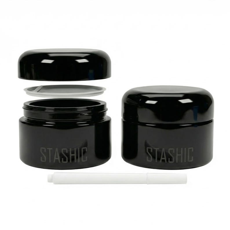 May include: Two black, cylindrical jars with lids, one open, and a white, cylindrical tool. The word "STASHIC" is printed on the side of each jar. The jars are made of a glossy material.