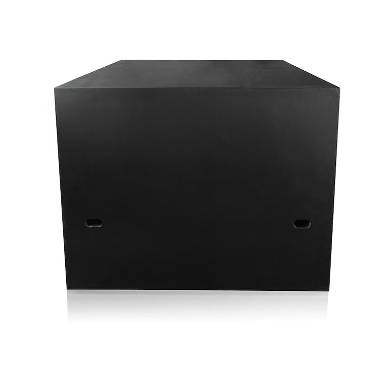 May include: A large, black, rectangular speaker cabinet with a flat top and two small, oval-shaped openings on the front. The cabinet is made of a solid, dark material and sits on a white surface.