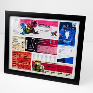 May include: A framed collage of vintage soccer tickets and memorabilia. The tickets are from different games and leagues, including the UEFA Champions League and the Coppa dei Campioni. The memorabilia includes a rooster logo and a trophy. The frame is black and the background is white.