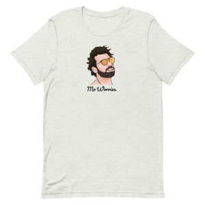 May include: A light grey t-shirt featuring a cartoon illustration of a man wearing sunglasses and a beard. The text "Mo Worries" is printed below the illustration.