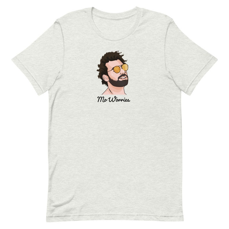 May include: A light grey t-shirt featuring a cartoon illustration of a man wearing sunglasses and a beard. The text "Mo Worries" is printed below the illustration.