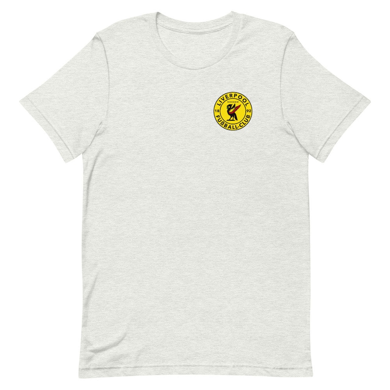 May include: A heather grey t-shirt with a yellow circle logo featuring a red bird and the text "Liverpool Football Club 1892".