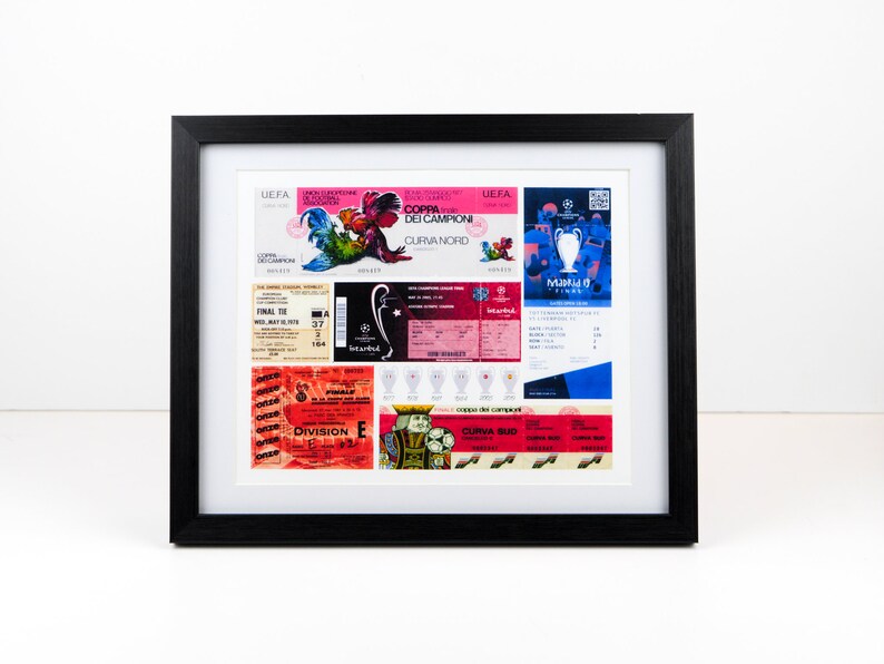May include: A framed collage of vintage soccer tickets and memorabilia. The tickets are from different games and leagues, including the UEFA Champions League and the Coppa dei Campioni. The memorabilia includes a small replica of the Champions League trophy and a few other items.