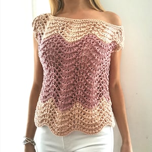 Puede incluir: Top de crochet en tonos beige y rosa. El top con hombros descubiertos presenta un escote y dobladillo festoneados. El diseño de tejido abierto crea un aspecto delicado y aireado. El top es una prenda de vestir elegante.