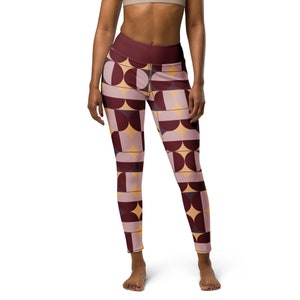Puede incluir: Un par de leggings con un patrón geométrico en tonos burdeos, rosa y dorado. Las leggings tienen cintura alta y una silueta ajustada.