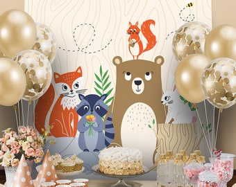 May include: A woodland-themed party table setting with a cake, cupcakes, and other treats. The backdrop features a brown bear, a fox, a raccoon, and a squirrel. Gold balloons with confetti are scattered around the table.